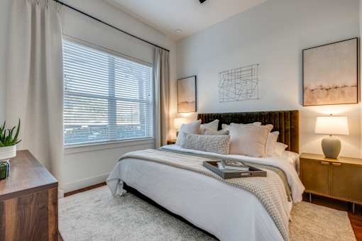 A bedroom with a large bed and two lamps.