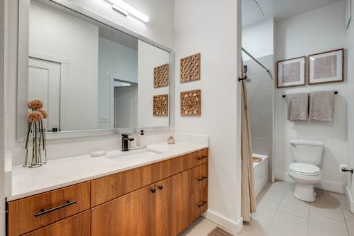 A bathroom with a white counter top and wooden cabinets.