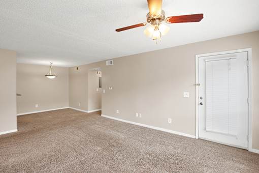 A room with a ceiling fan and carpeted floor.