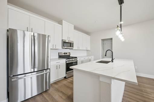A modern kitchen with a stainless steel refrigerator and white cabinets.