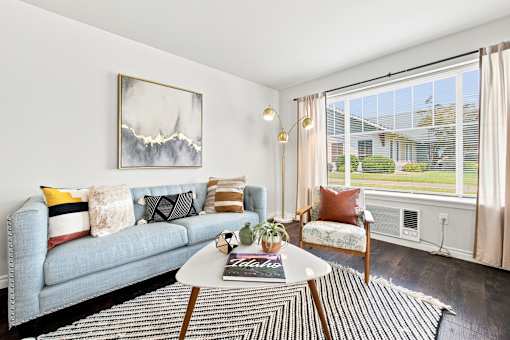 A living room with a grey couch, a coffee table, and a painting on the wall.