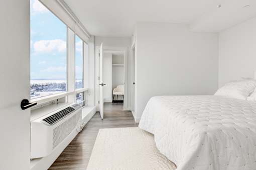 A bedroom with a large bed and a window with a view of the city.