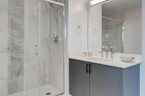 A bathroom with a marble shower and a white sink.