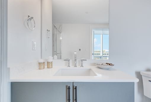 A white sink in a bathroom with a large mirror above it.