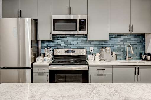 A kitchen with a stove, refrigerator, and microwave.