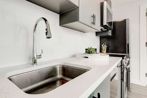 A modern kitchen with a stainless steel sink and a black refrigerator.