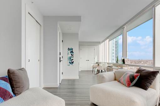 A living room with a white couch and a view of the city.
