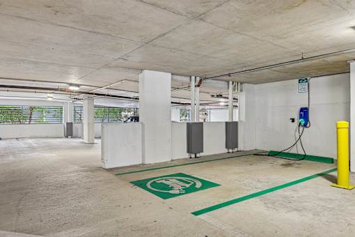 A parking garage with a green electric vehicle charging station.