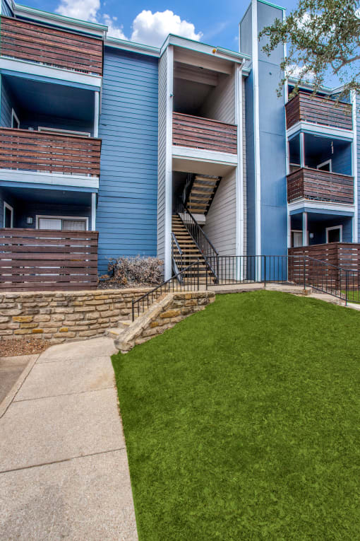 a view of the back of an apartment building with a grassy area in front of it