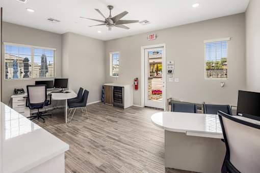 A spacious office with a white reception desk and a ceiling fan.