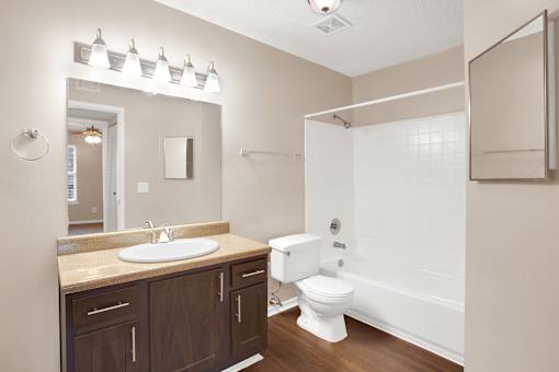 A white toilet is in a bathroom with a sink and mirror.