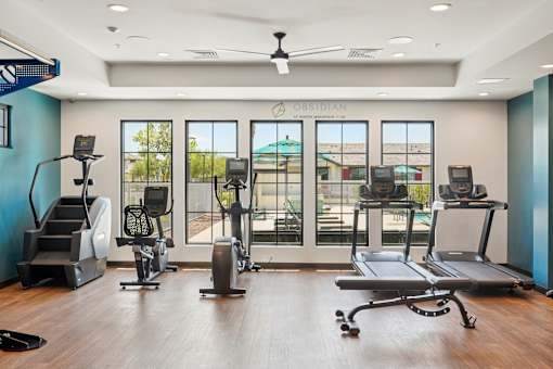 A gym with a variety of equipment including treadmills, stationary bikes, and weight machines.