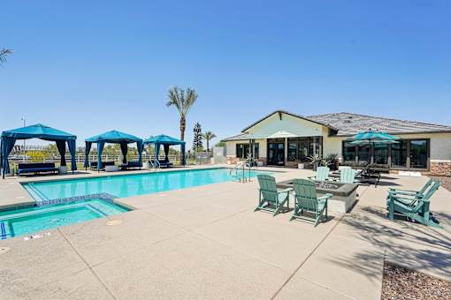 A pool area with a blue umbrella and green chairs.