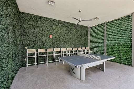 A ping pong table is in the middle of a room with a green wall.