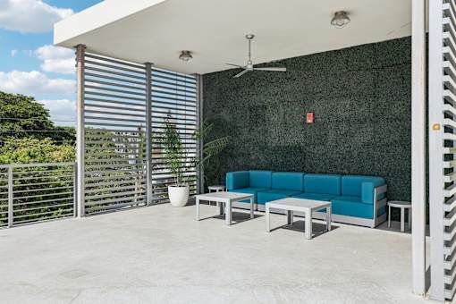 A blue couch is on a patio with a ceiling fan.