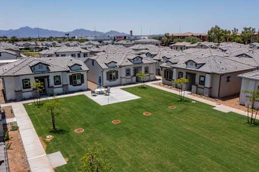 Pet-Friendly Apartments in Phoenix AZ - The Crofton at Sheely Farms - Aerial View of the Property and Community, with a Grassy Lawn in the Middle