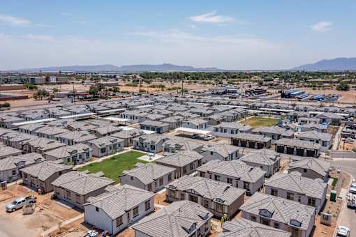 A large housing development with numerous houses and a green space in the middle.