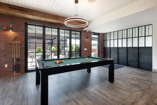 a pool table in a living room with a brick wall