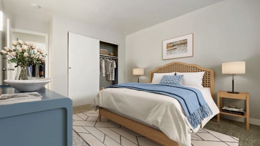 A bedroom with a bed, a nightstand, and a vase of flowers.