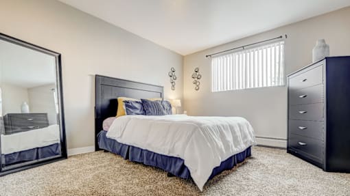 A bedroom with a large bed, a dresser, and a mirror.
