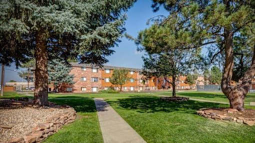 A tree-lined walkway leads to a building.