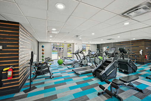 Fitness room in Amber Grove Apartments featuring treadmills, ellipticals, and weight machines