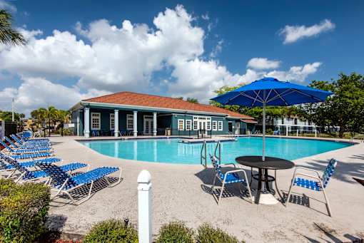 A pool area with blue chairs and a white building in the background.