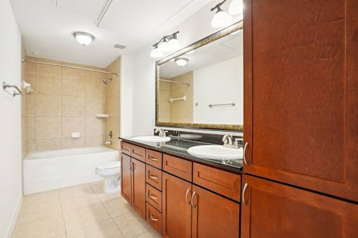 A bathroom with a white tub, sink, and wooden cabinets.