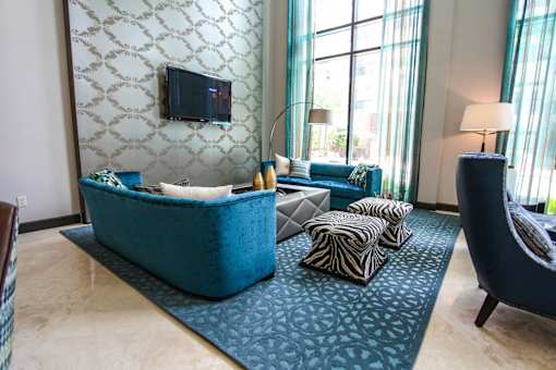 A living room with a blue couch and a television on the wall.