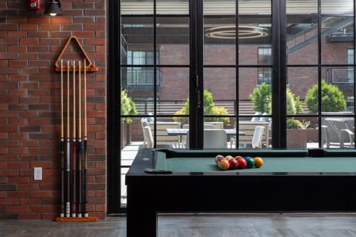 a pool table in a living room with a brick wall