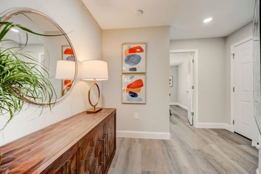 Lady Lake, FL Rentals – The Groves at Lake Ella - a hallway with a mirror and a wooden dresser with a plant