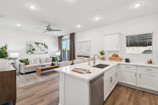 A modern kitchen with white cabinets and a wooden floor.