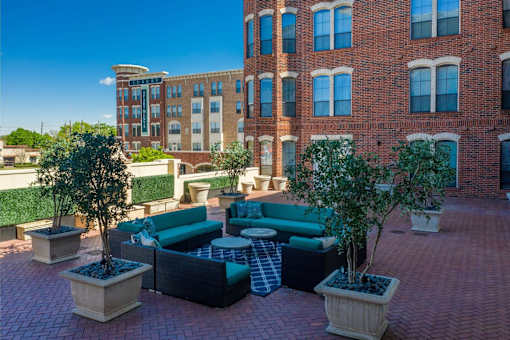 A courtyard with a brick building in the background and a green couch.