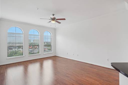 A room with a ceiling fan and three windows.