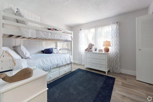 A white bedroom with a bunk bed and a dresser.