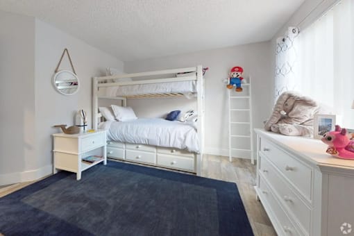 A white bedroom with a bunk bed and a dresser.