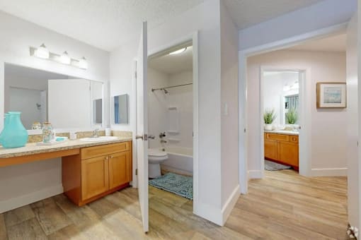 A bathroom with a sink, mirror, and wooden floors.