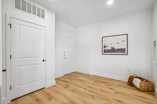A room with a white door, a picture on the wall, and a basket on the floor.
