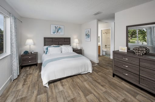 A bedroom with a large bed, two nightstands, and a dresser.