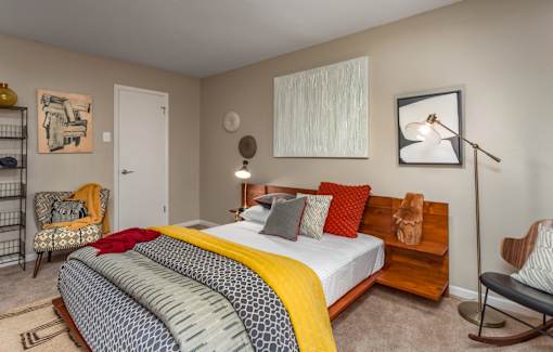 A bedroom with a bed, chair, and lamp.