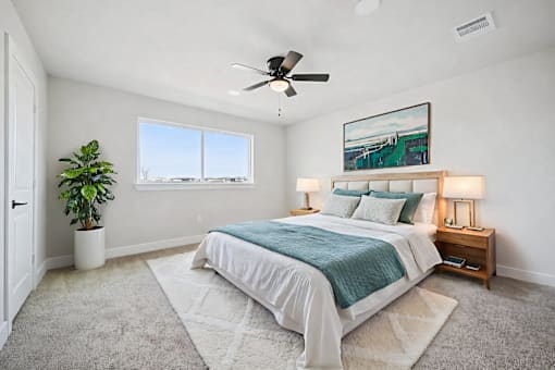 A bedroom with a large bed, a ceiling fan, and a painting on the wall.