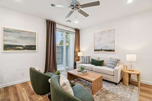 A living room with a green chair, a white couch, and a painting on the wall.