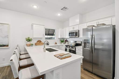 A modern kitchen with a white countertop and stainless steel appliances.