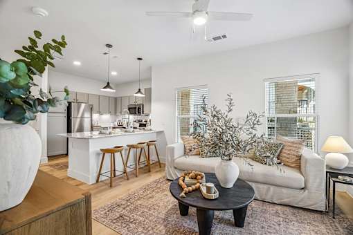 A modern living room with a kitchen in the background.