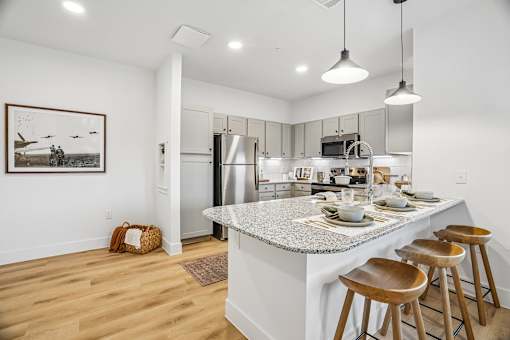 A kitchen with a white island and wooden bar stools.