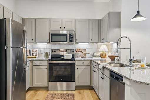 A kitchen with a refrigerator, oven, microwave, and sink.