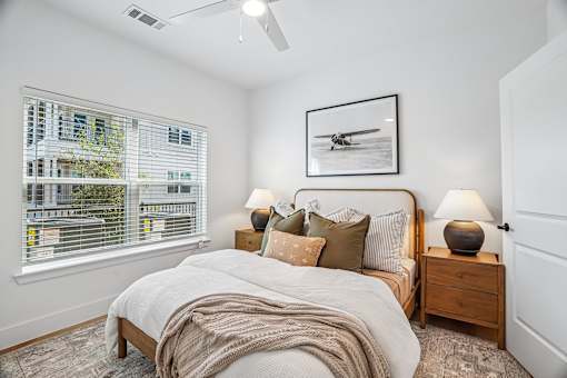 A bedroom with a bed, nightstand, and a picture of a plane on the wall.