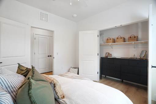 A bedroom with a bed, dresser, and shelves.