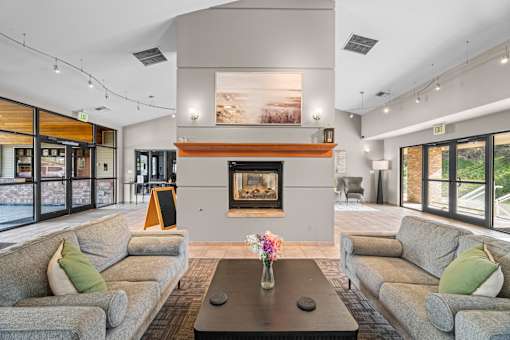 A living room with a fireplace and two grey couches.