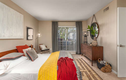 A bedroom with a large bed and a window with curtains.